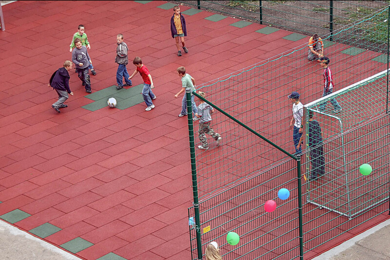 Blick von schräg oben auf einen Bolzplatz oder ein Kleinspielfeld aus Ballspielplatten von WARCO. Eine Gruppe von Kindern spielt Fußball.