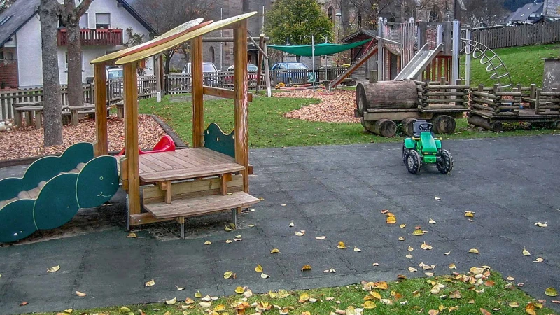 Un grande parco giochi naturale a Olsberg, realizzato con le lastre antitrauma WARCO in colore verde con una casetta in legno.