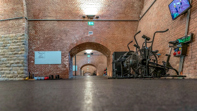 Splendida sala grande con le archi che è stata trasformata in uno studio di fitness e rivestita con tappeti sportivi marroni di WARCO.