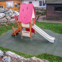 Auf einem Hanggrundstück wurde vor der Stützmauer ein Kleinkinderspielplatz, bestehend aus einem Kleinkinderspielhaus mit Rutsche, errichtet. Der Fallschutz erfolgt fachgerecht mit Fallschutzmatten nach EN 1177.