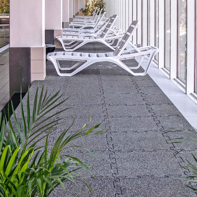 Le carrelage WARCO en couleur granit clair installé dans un espace de repos avec les chaises longues dune piscine intérieure.