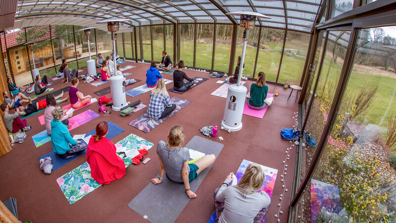 La salle de yoga avec des tapis sportifs WARCO en rouge brique, où de nombreux élèves de yoga font leurs exercices.
