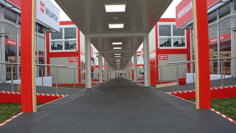 Un percorso coperto conduce alle singole aree tematiche dei Würth Information Days 2019. Tutte le aree del pavimento sono rivestite con le piastrelle nere del pavimento espositivo WARCO.