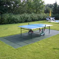 Unter einer Tischtennisplatte im Garten liegt ein Sportboden aus grünen WARCO Fallschutzplatten.