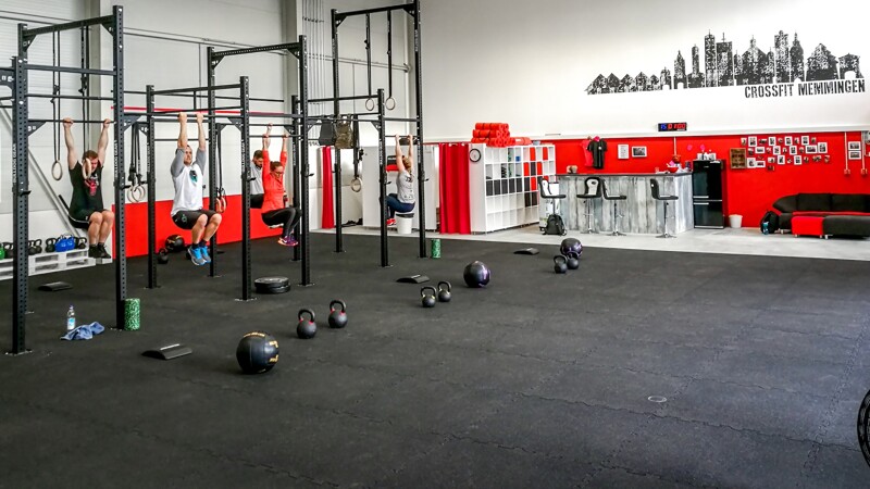 Les athlètes s'entraînent sur les racks dans un hall de CrossFit à Memmingen, équipé des tapis sportifs pour protection de sol noirs pour CrossFit de WARCO.