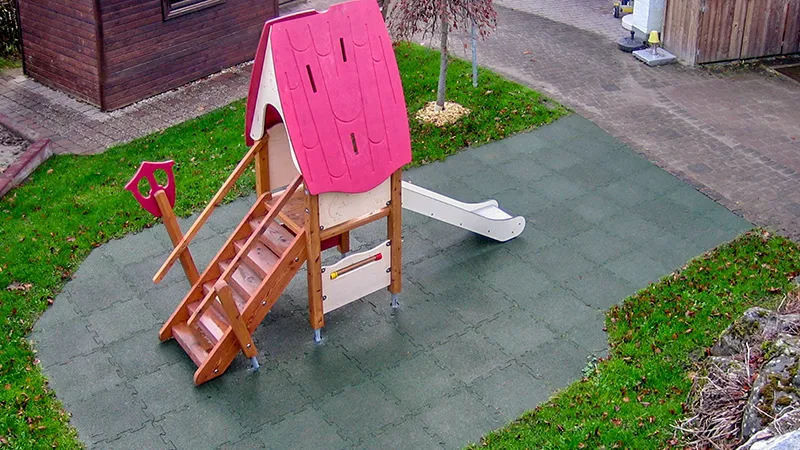 Fallschutzmatten auf einem Spielplatz mit effektiven Fallschutz unter einem Spielhaus mit geringer Fallhöhe.